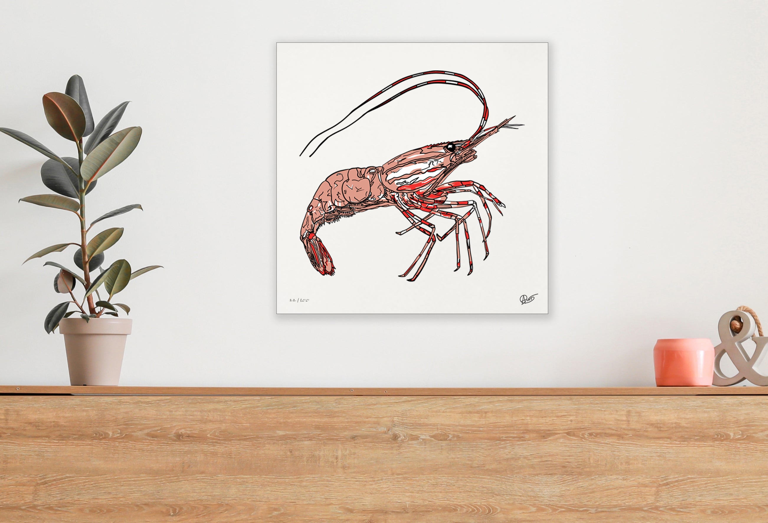 Artwork of a spotted prawn on a white wall above a wooden surface with a plant and decorative items.