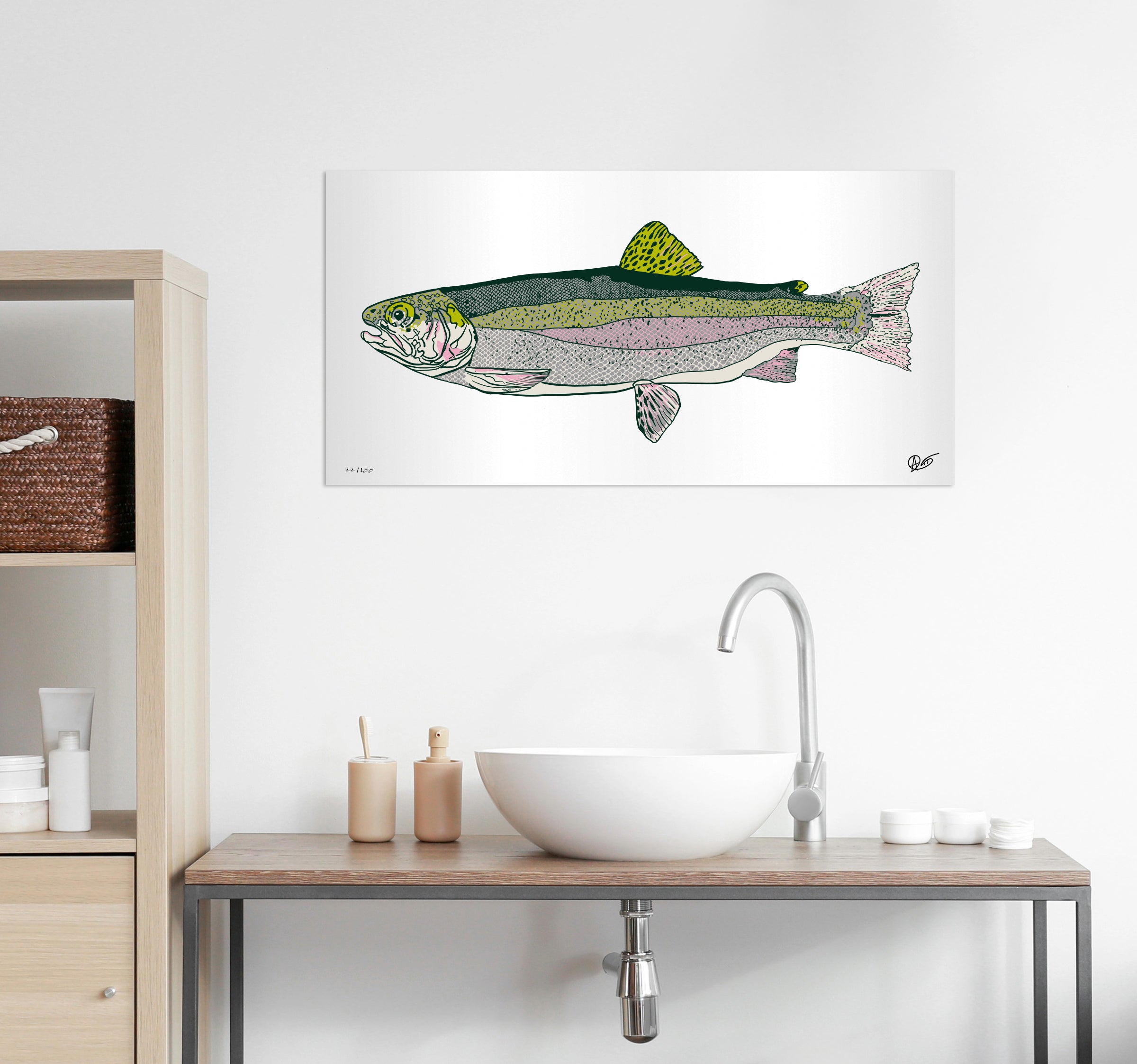 Rainbow trout metal print on a wall above a bathroom sink with wooden cabinets.