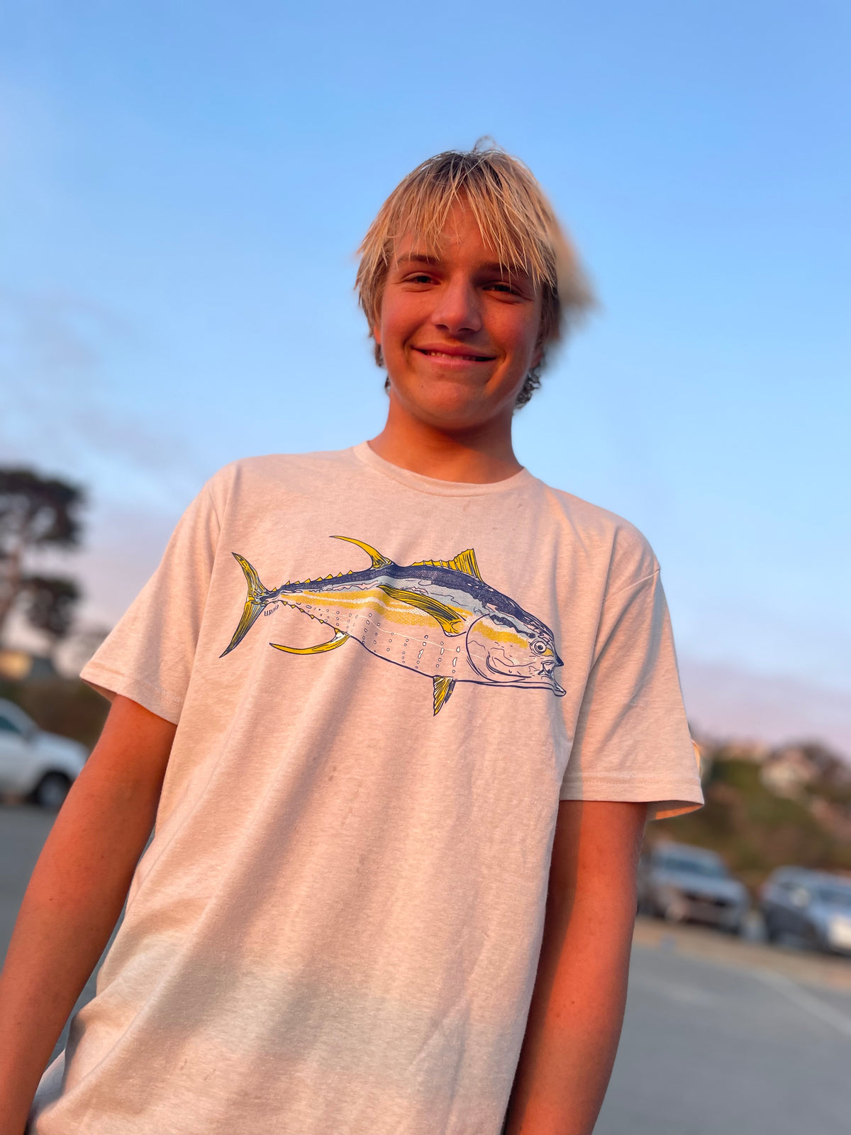 Uroko Ambassador, Harper King, wearing a light beige t-shirt with a graphic print of a tuna fish on the front.