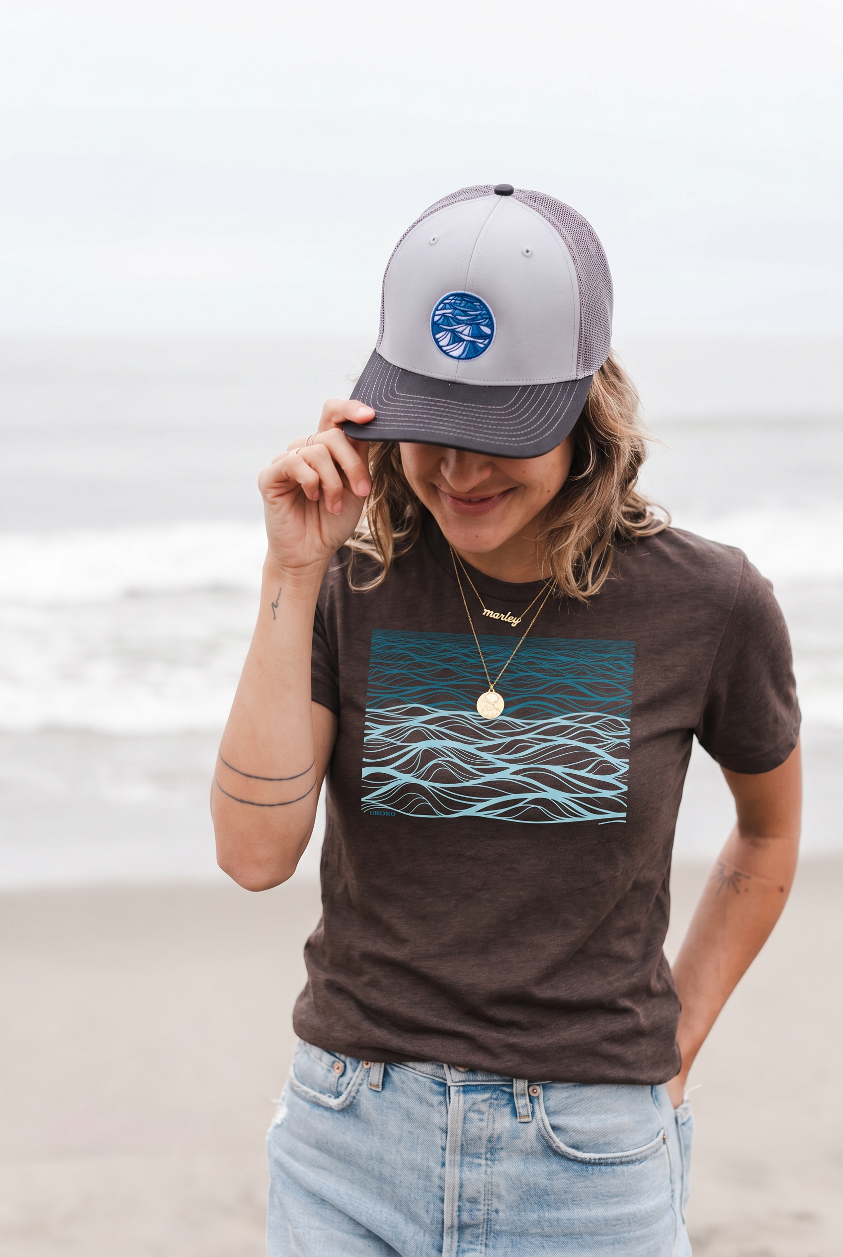 Person wearing a cap and t-shirt with a wave design on a beach