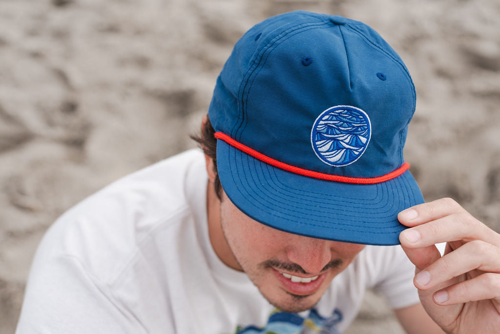 Person wearing a grandpa hat outdoors near the coast